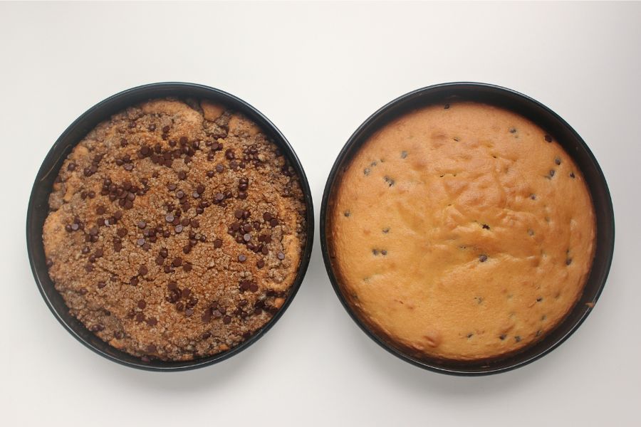 Two round cake pans showing crumb topping with chocolate chips on one cake and baked yellow cake layer in the other