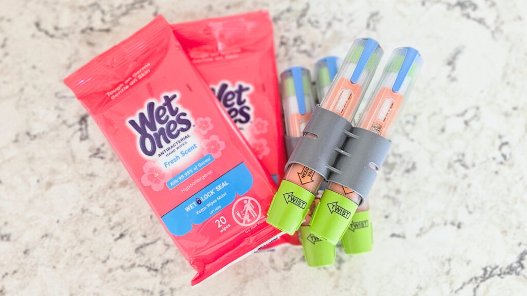 Wet Ones antibacterial wipes package and EpiPen auto-injectors on a white marble surface