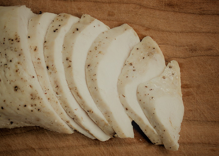 Overhead view of chicken sliced on a wood cutting board