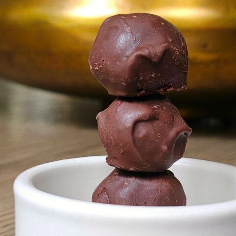 3 chocolate truffles stacked vertically in a white bowl