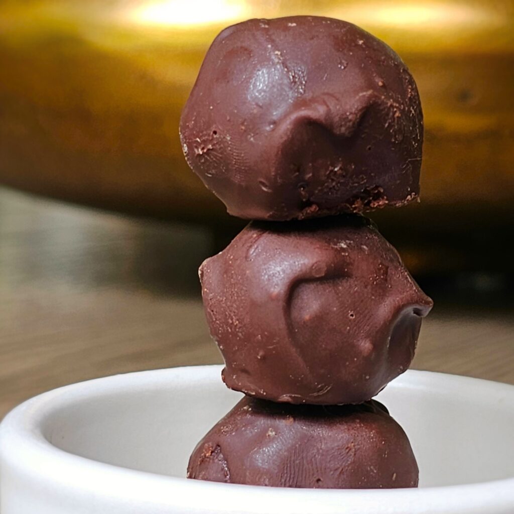 three chocolate truffles stacked vertically in a white bowl