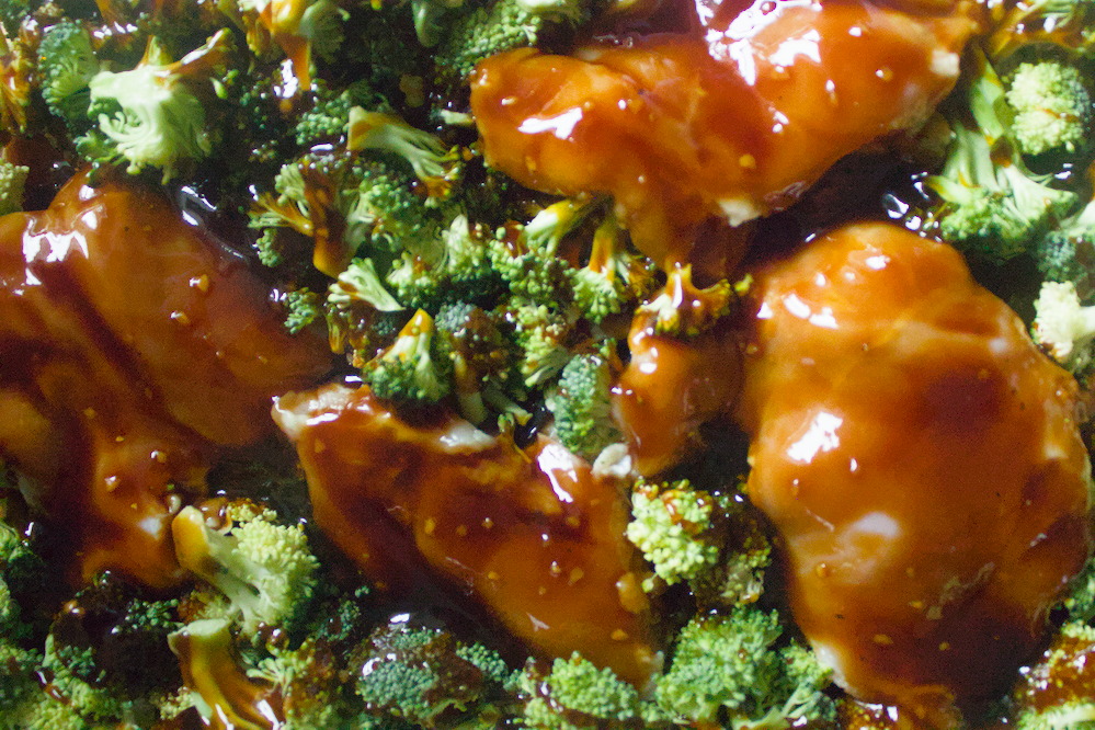 Overhead view of raw chicken breast and broccoli coated with teriyaki saice and ready to bake.